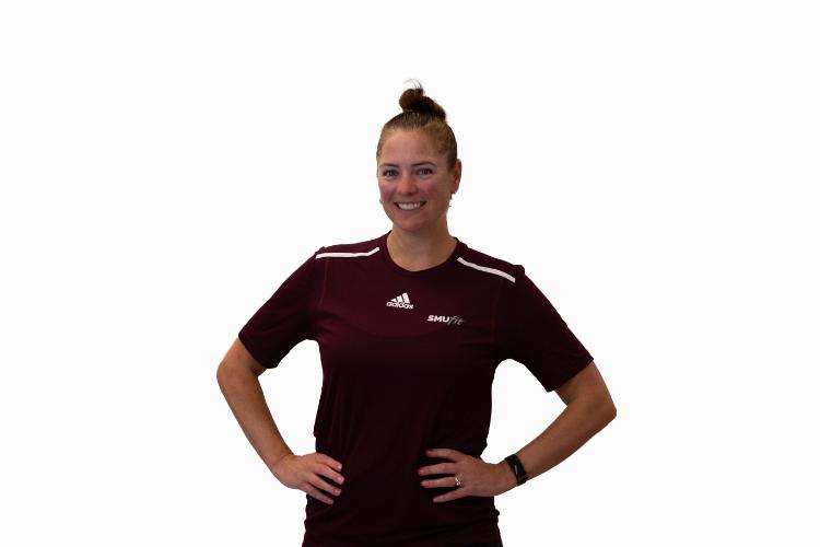 A white female trainer with her hands on her hips.