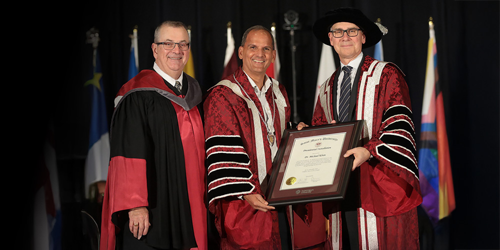 Three people in ceremonial robes holding a parchment.